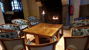 Un comedor acogedor con una mesa y sillas de madera, una chimenea y vistas al exterior a través de una ventana.