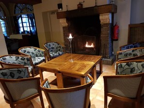 Un comedor acogedor con una mesa y sillas de madera, una chimenea y vistas al exterior a través de una ventana.