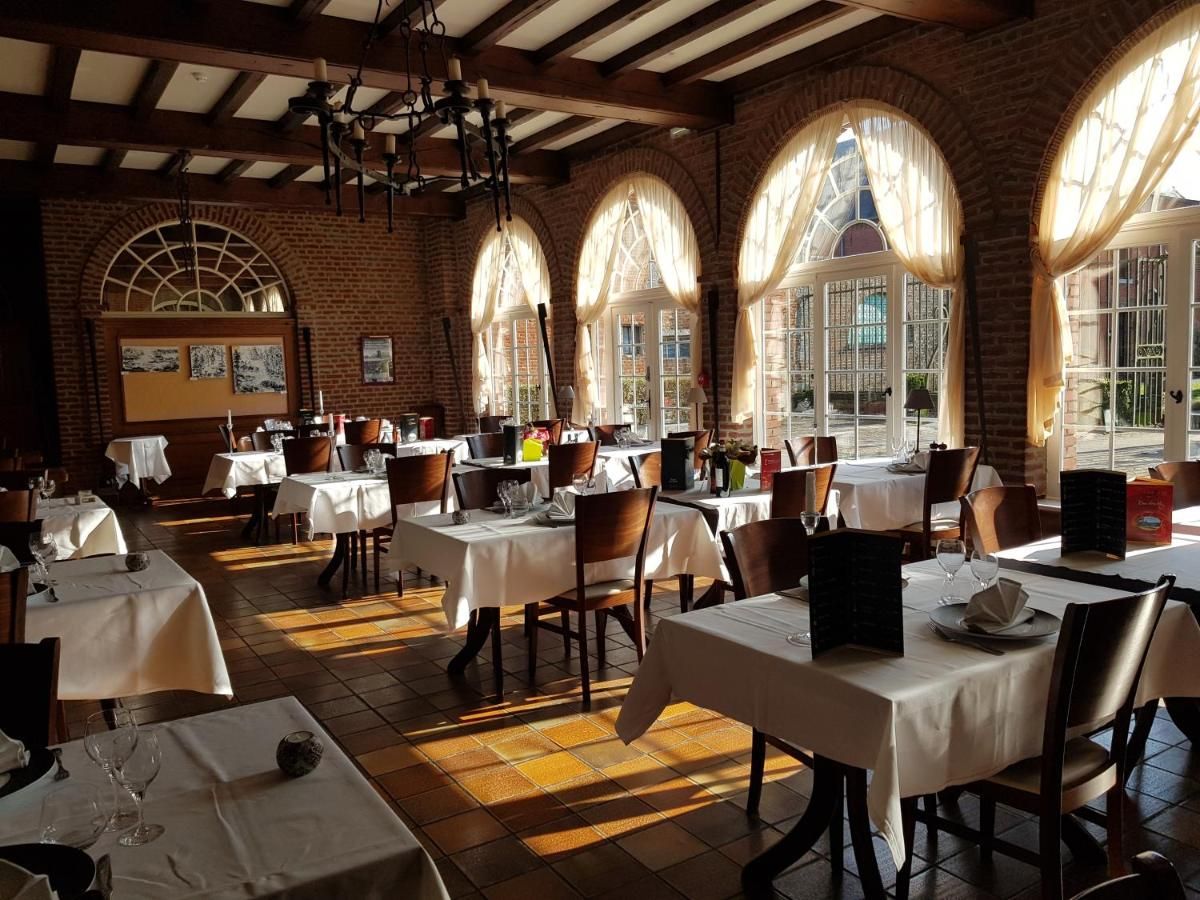 A restaurant with multiple tables and chairs, brick walls, and large windows with curtains.