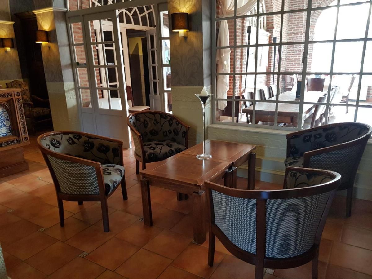 A dining area with a wooden table and four chairs, a vase on the table, and a view through a window.