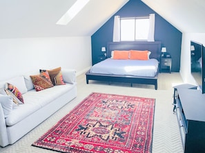 A bedroom with a bed, a white sofa, a red rug, and a window with curtains. - The Little Black House - in the heart of RiNo! (Denver)