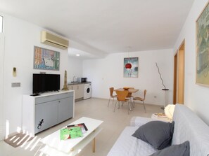 Un espacio habitable compacto con kitchenette, zona de comedor, sofá y televisor.