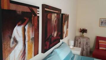 Une chambre à coucher avec un lit, une table de chevet et deux tableaux abstraits accrochés au mur.