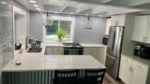 A modern kitchen with a central island, stainless steel appliances, and a window with a view of greenery. - Blue Ridge Riverfront Cabin•2-Level Deck•Sleeps 8 (Blue Ridge)