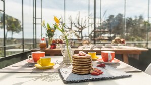 A breakfast setup with pancakes, strawberries, and coffee cups on a table with a view of trees and a clear sky. - Villa Ada trulli in Puglia (Martina Franca)
