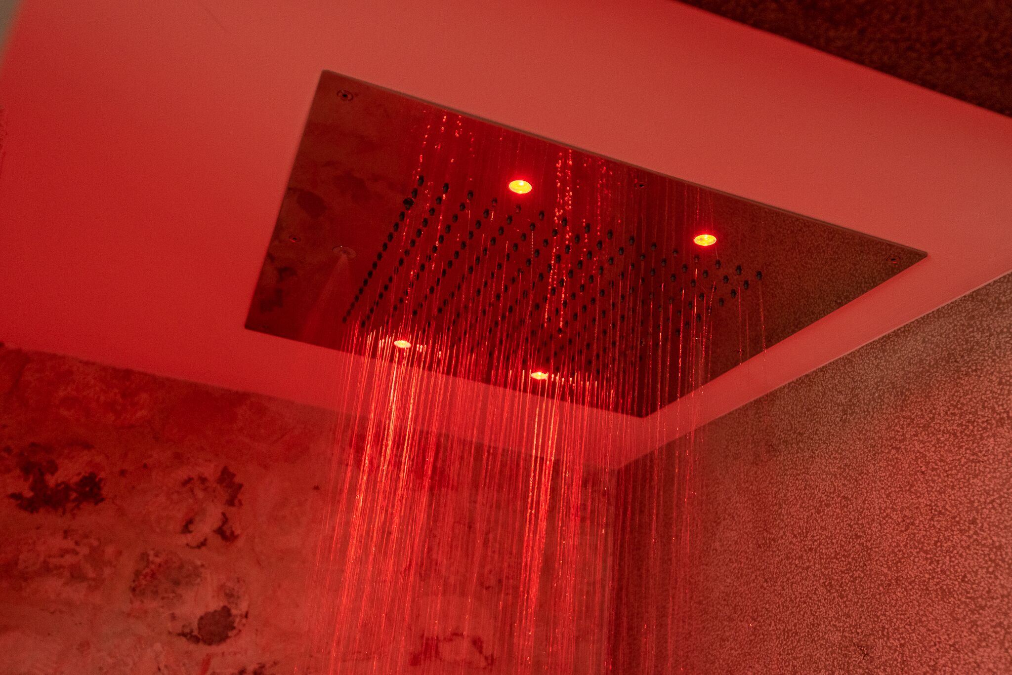 Un pommeau de douche doté de plusieurs jets et d’un éclairage rouge.