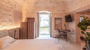 A bedroom with a bed, a desk, a chair, a TV, and a plant. - Villa Ada trulli in Puglia (Martina Franca)