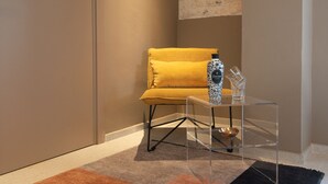A room with a mustard-colored armchair, a clear glass coffee table, and a decorative vase. - Villa Ada trulli in Puglia (Martina Franca)