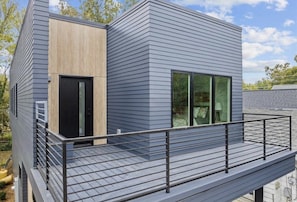 A modern two-story building with a balcony and a wooden door.