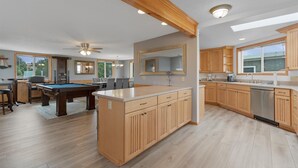 Une cuisine spacieuse dotée de meubles en bois, d’un îlot central et d’un coin repas avec une table de billard.