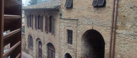 A stone building with arched doorways and a narrow street.