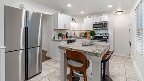 A modern kitchen with white cabinetry, stainless steel appliances, and a granite countertop.