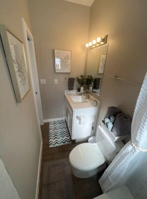 Bathroom features a toilet, sink, and mirror with overhead lighting.