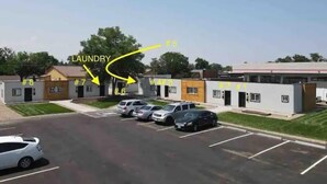 A parking lot with several cars and a building labeled "LAUNDRY" with numbered doors. - Chic & intimate 2 bedroom (Brighton)