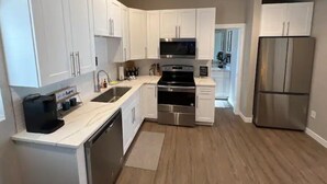 A modern kitchen with white cabinets, stainless steel appliances, and a wooden floor. - Chic & intimate 2 bedroom (Brighton)