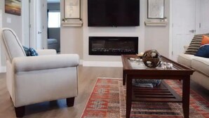 Una sala de estar con una televisión de pantalla plana sobre la chimenea, un sofá y una mesa de centro.