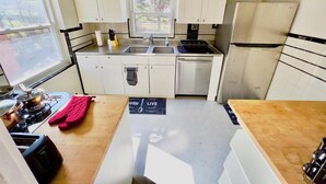 Une cuisine de taille réduite avec des meubles blancs, un réfrigérateur en acier inoxydable, une cuisinière et un évier.