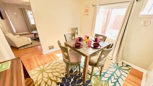 Un coin repas avec une table dressée pour quatre personnes, entourée de chaises.