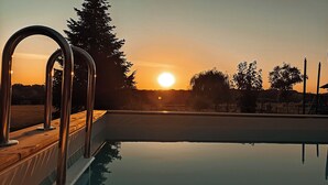 Una piscina con barandales metálicos y vistas a la puesta de sol.