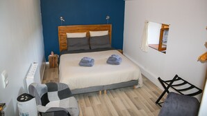 Un dormitorio con cama, una silla, una mesita y un espejo en la pared.