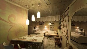 A cozy room with a dining table, chairs, a sofa, and a bed. There are pendant lights hanging from the ceiling.