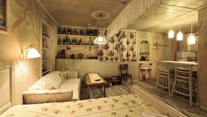 A cozy room with a sofa, a small table, a bar area with bottles, and a dining set.