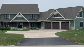 Une maison à deux étages avec une allée menant à l’entrée, un garage et un panier de basketball.