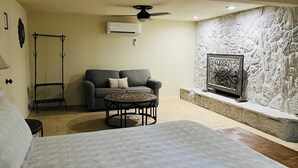A modern living room with a sofa, a coffee table, a bed, and a stone accent wall. - Maplewood Haven (Daphne)