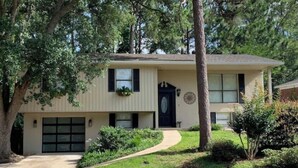 A two-story house with a front garage, a covered porch, and a landscaped yard. - Maplewood Haven (Daphne)