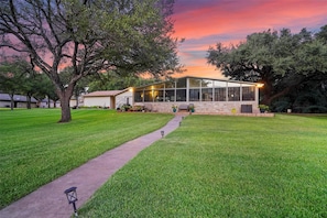 A modern house with a large glass facade, surrounded by a well-maintained lawn and trees. - Shorhaus, Gorgeous Main Body Lake Retreat (Granbury)