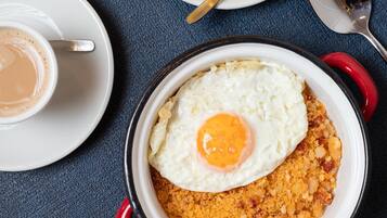 Ein Frühstückstisch mit einer Suppenschüssel, einer Kaffeetasse und einem Teller mit Spiegelei auf zerbröselter Nahrung.