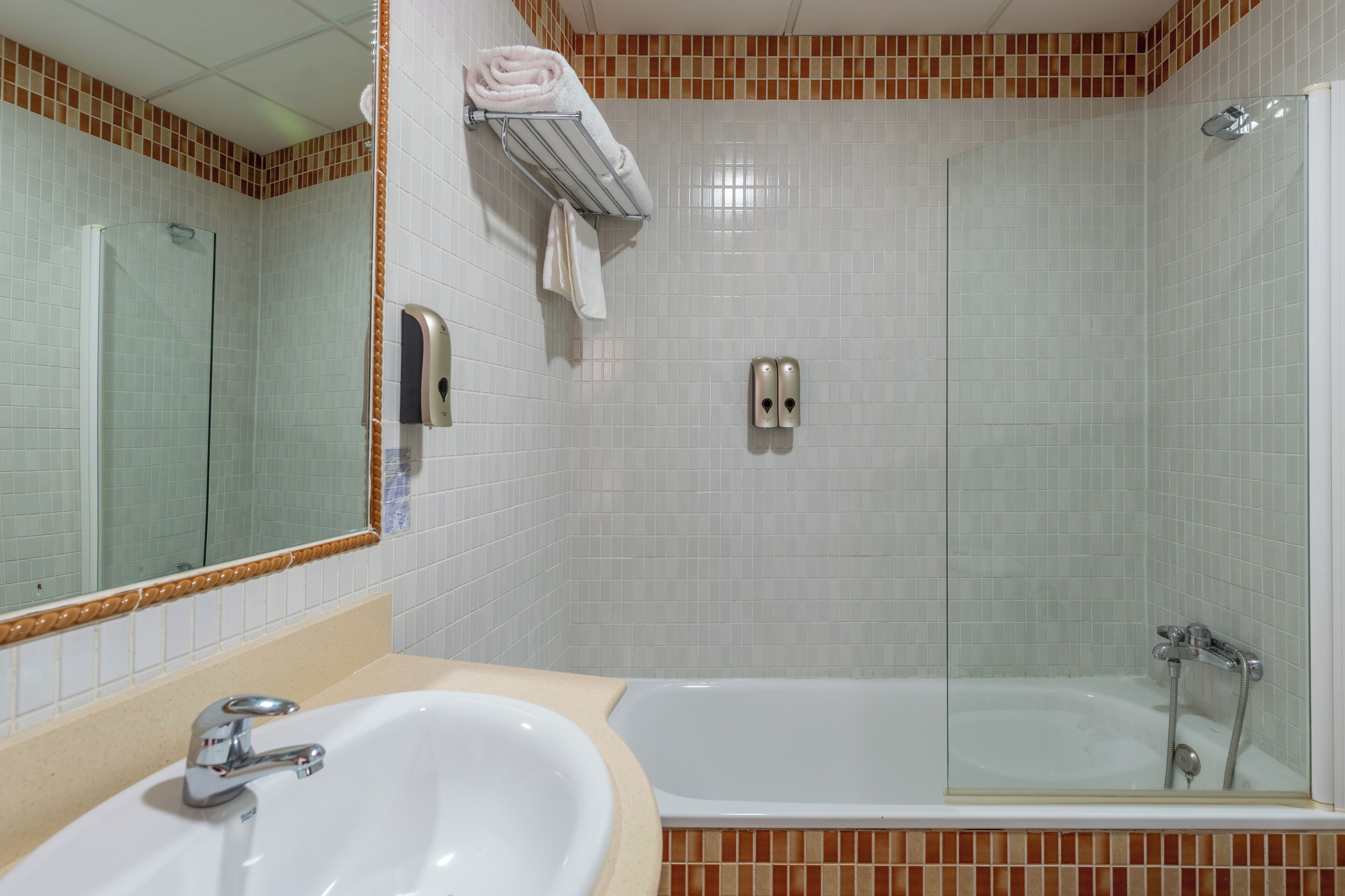 A bathroom with a sink, mirror, and a glass-enclosed shower.