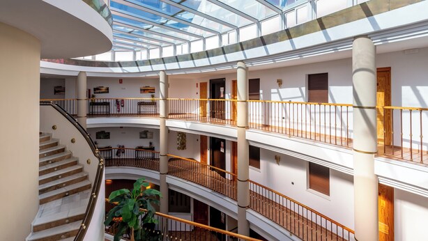 A multi-level atrium with glass ceilings, a central staircase, and multiple balconies.