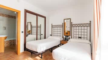 A hotel room with two beds, a bathroom, and a shower area.