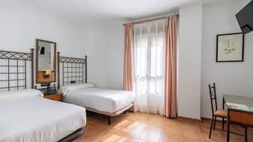 Habitación de hotel con dos camas, un escritorio, una silla, un espejo y una ventana con cortinas.