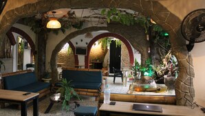 A cozy interior with stone arches, wooden furniture, and a water feature. - Grand ilama Hotel (Cali)