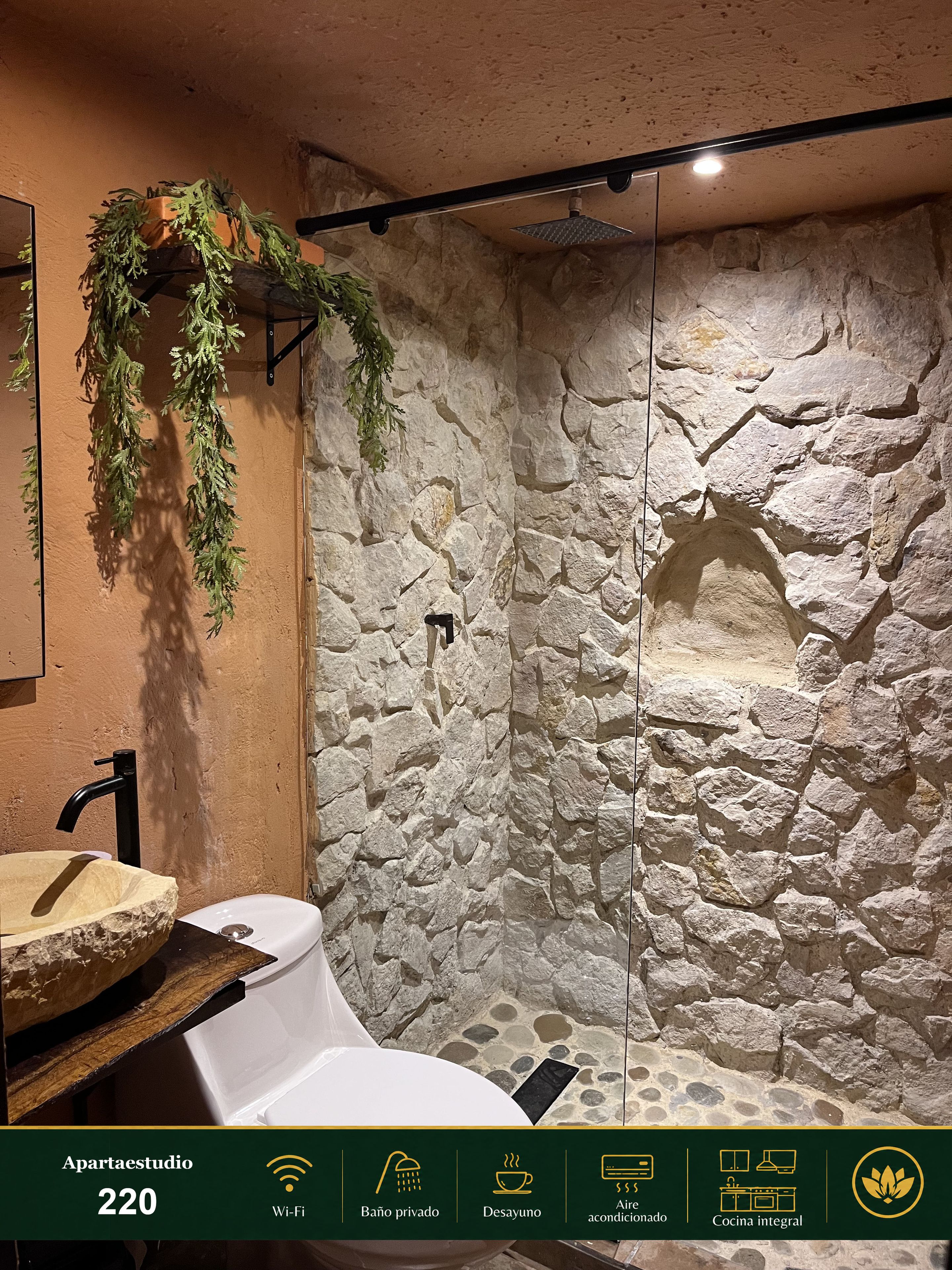 A bathroom with a stone wall, a sink, and a shower area.