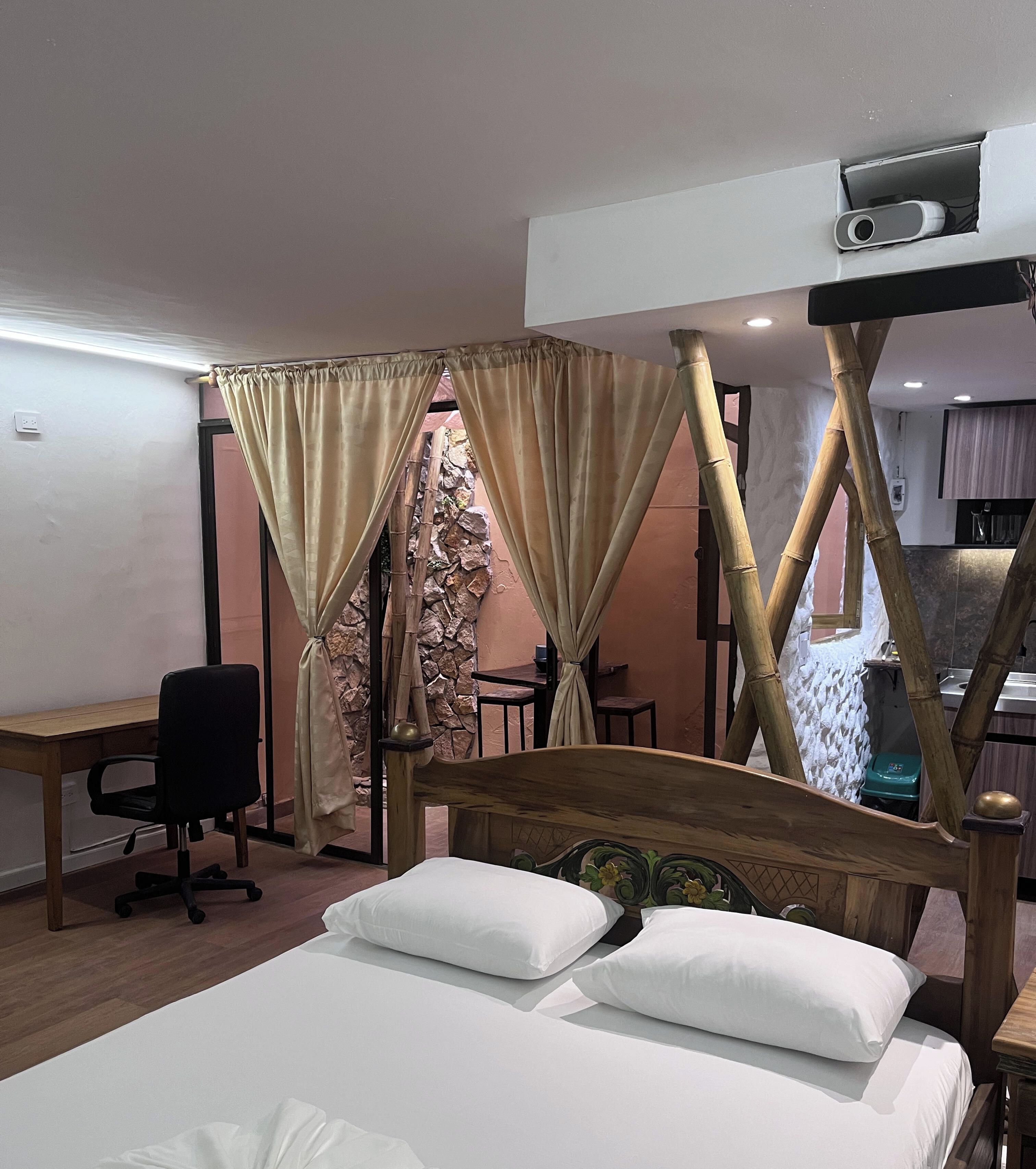 A hotel room with a bed, desk, chair, and a bathroom with a shower.