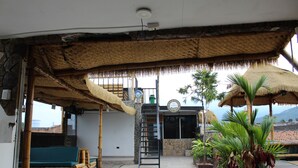 A covered outdoor area with a wooden bench, a ladder, and a thatched roof structure. - Grand ilama Hotel (Cali)