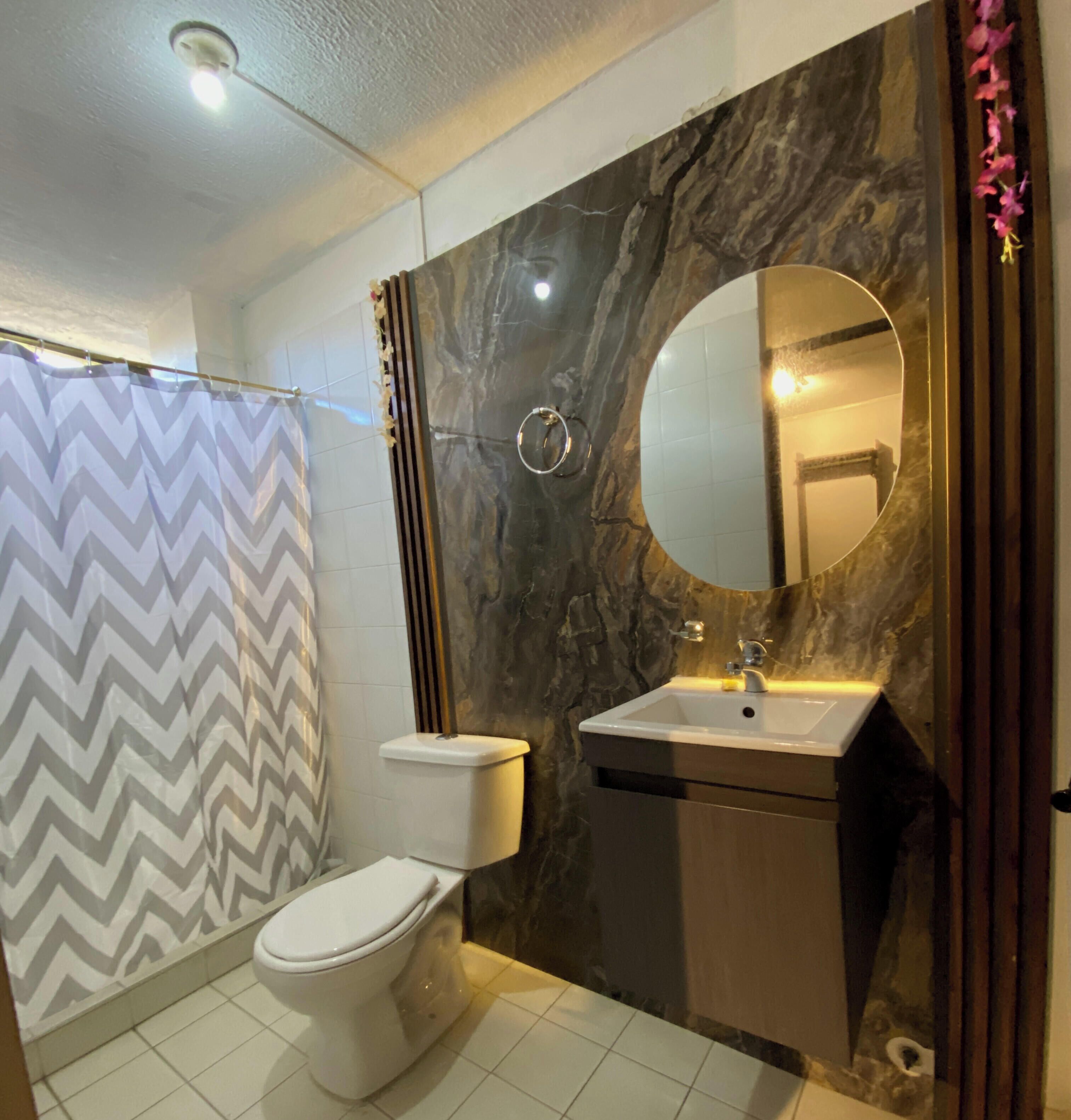 A bathroom with a toilet, sink, and shower area.