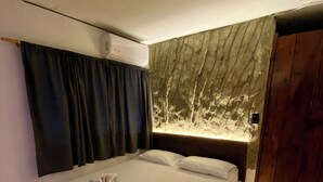 A modern hotel room with a large bed, dark curtains, a wall-mounted air conditioner, and a wooden floor. - Grand ilama Hotel (Cali)