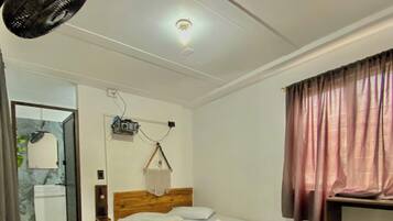 Un dormitorio con una cama de madera, una mesita de noche, una lámpara colgante, un espejo y una ventana con cortinas.
