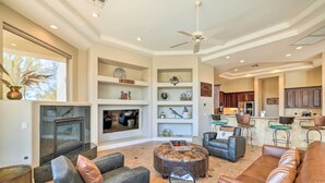 A spacious living room with a fireplace, comfortable seating, and a kitchen in the background.