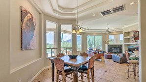 A spacious living room with a large dining table, comfortable seating, a fireplace, and a view of the outdoors.