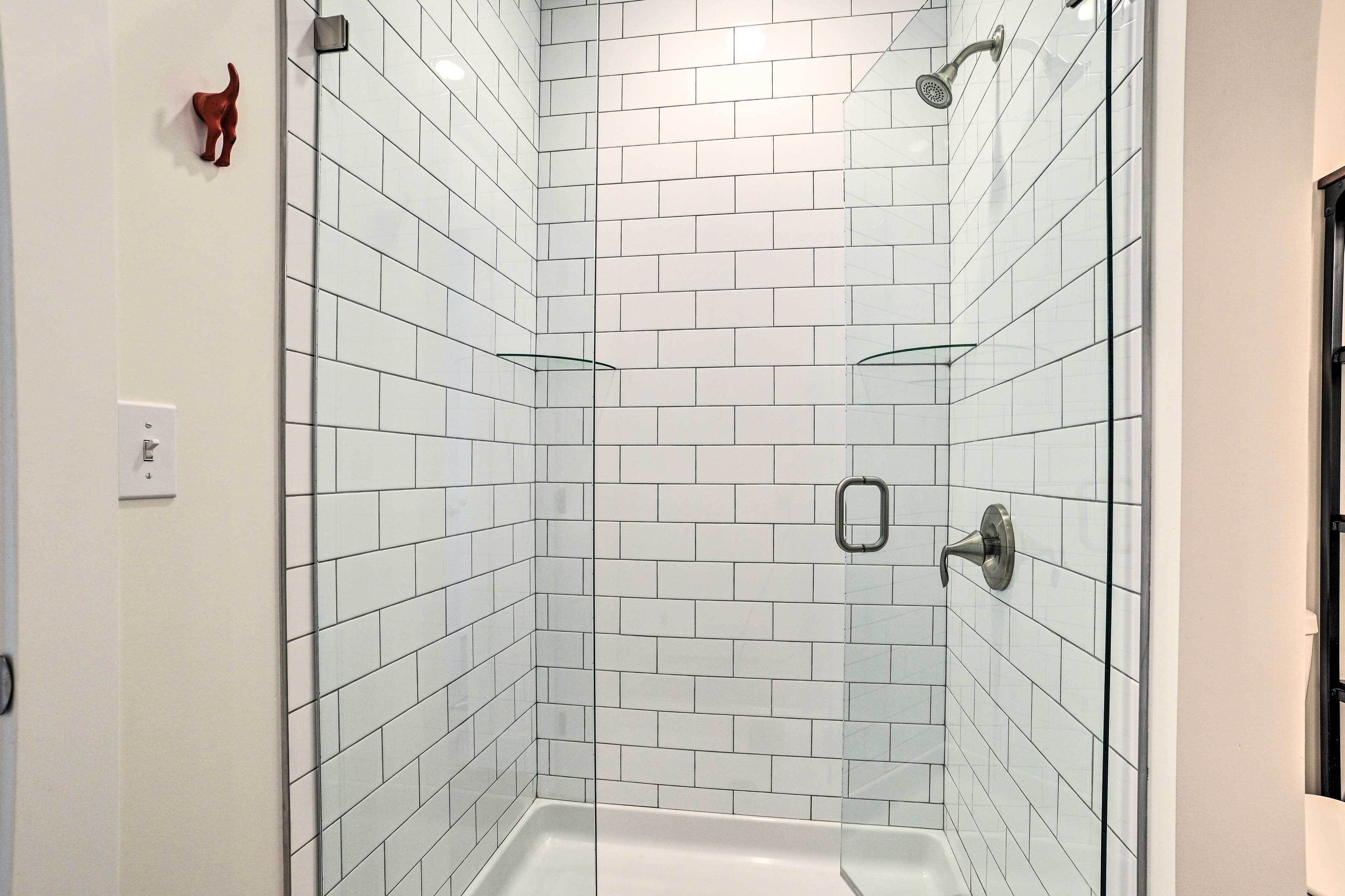 A corner shower with white subway tiles and a glass door.