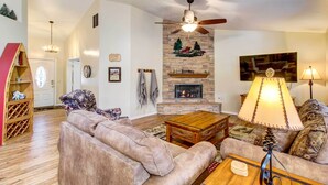 Una sala de estar acogedora con chimenea, ventilador de techo y una mesa de centro de madera.