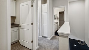 A hallway with white doors, a small countertop, and a dark wall with a circular design.