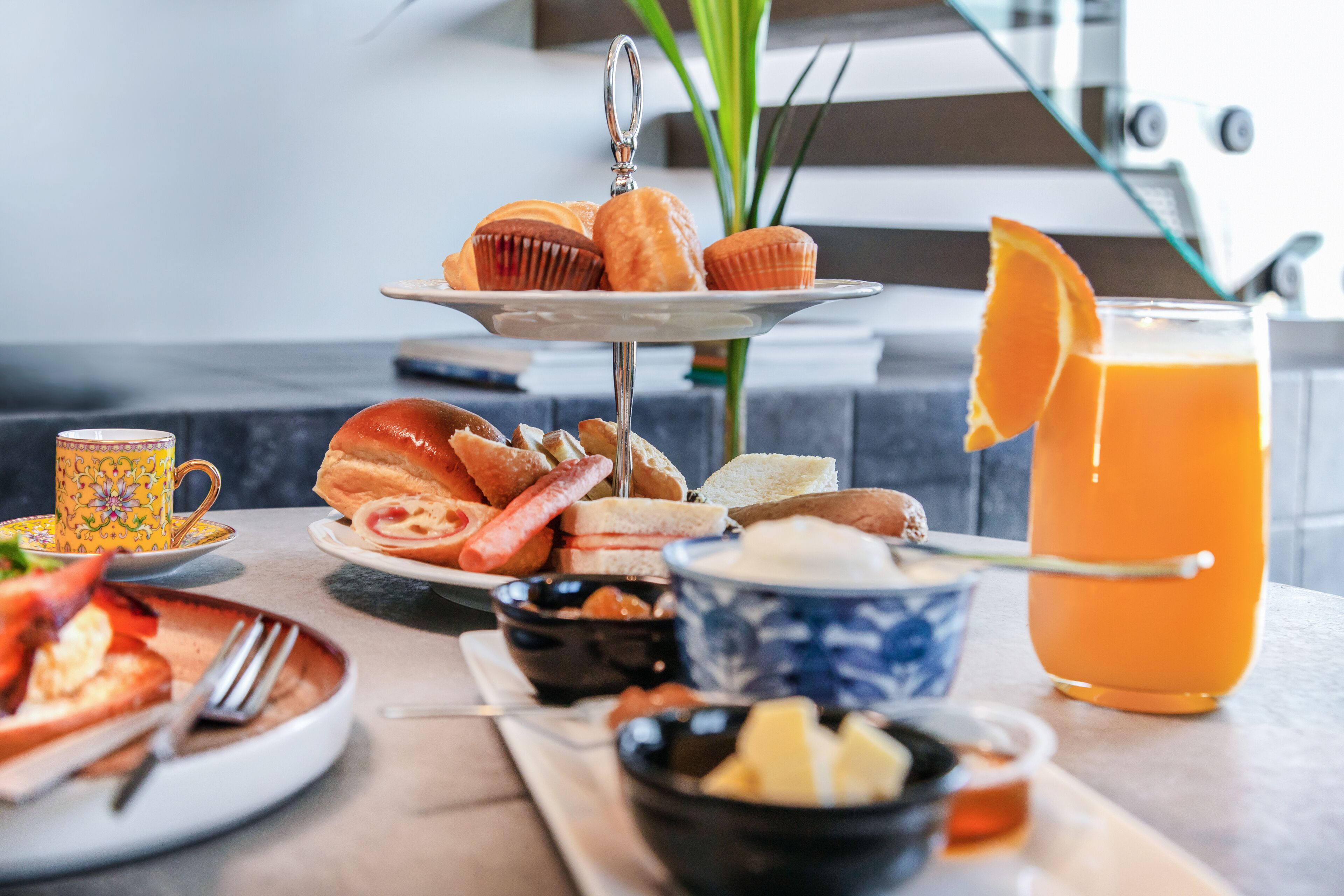 A breakfast setting with a variety of food items including pastries, sandwiches, and a glass of orange juice.