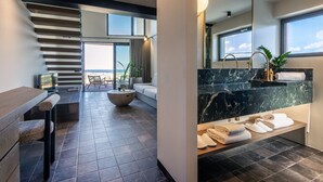 Un baño moderno con encimera de mármol, un espejo grande y vistas a la ciudad.