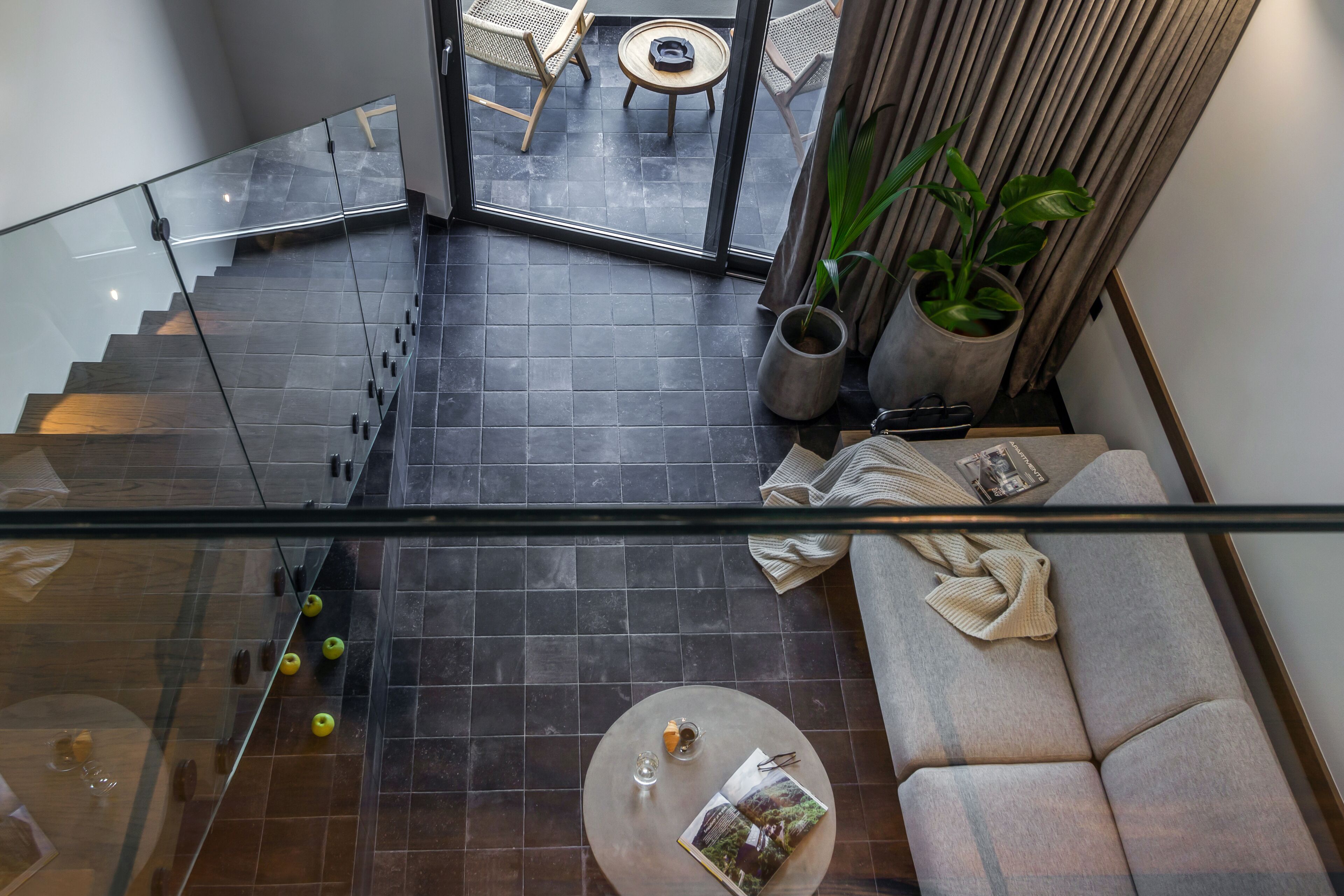 A modern interior with a glass railing, a staircase, a sofa, a coffee table, and a view of the outdoor area.